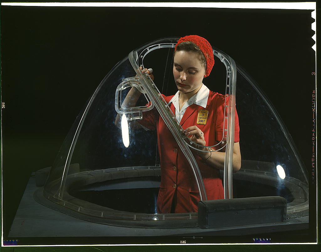 woman working on the nose of a bomber plane.