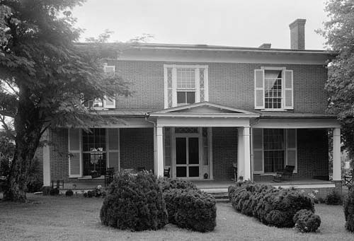 Avery's home. It is a two story house with a large patio. It has trees in the foreground.